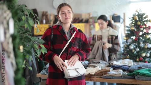 Positive young woman looking for little shoulder bag during X-mas sell-out in retail outlet