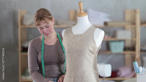 Dressmaker constructing custom dress on mannequin in sewing workshop