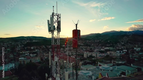 Telecommunication tower with cellular antennas for 5g mobile internet network in urban city at sunset, suntise