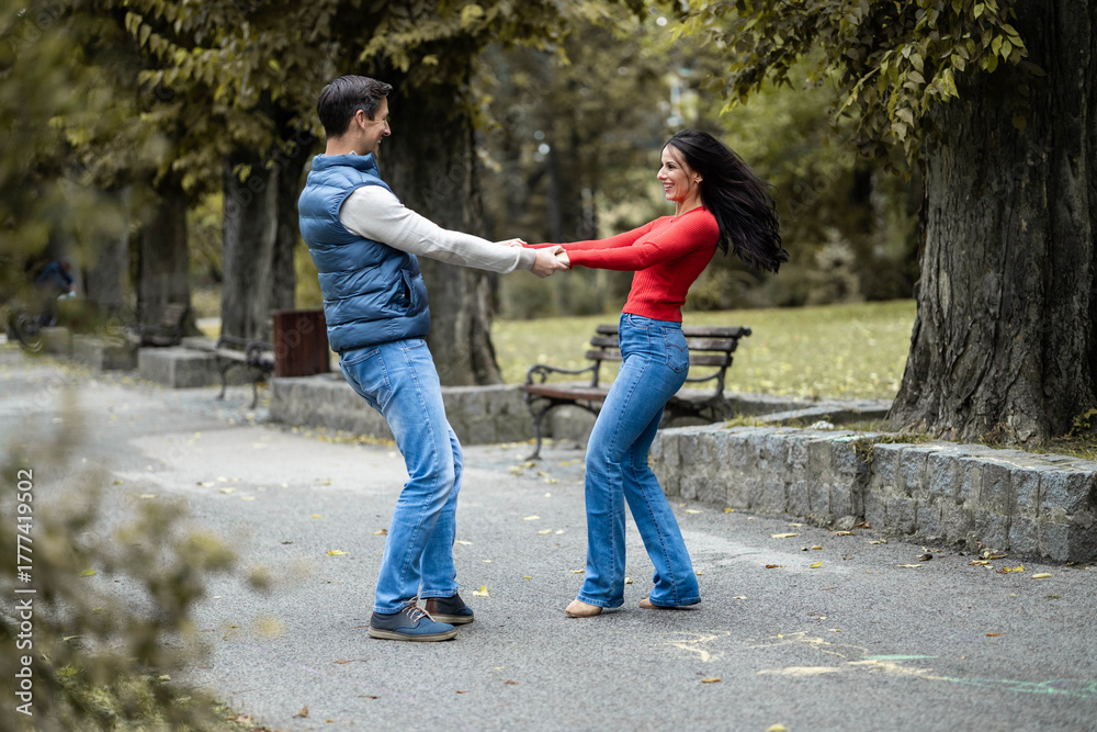 Obraz premium In a delightful outdoor scene, a couple joyfully dances together, expressing their love and happiness amidst the serene autumn landscape, showcasing a beautiful connection between them.