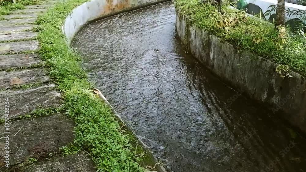 Water flowing through a concrete canal with green grass on the side