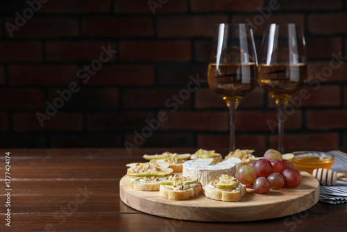 Delicious bruschettas served with camembert, grapes and wine on wooden table. Space for text