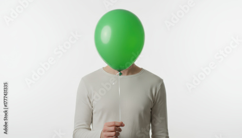 Person holding green balloon on white, calm mood