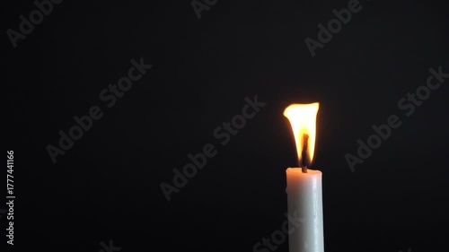 Glowing candle flame flickering gently in the darkness, creating a peaceful and serene atmosphere for meditation or remembrance videos