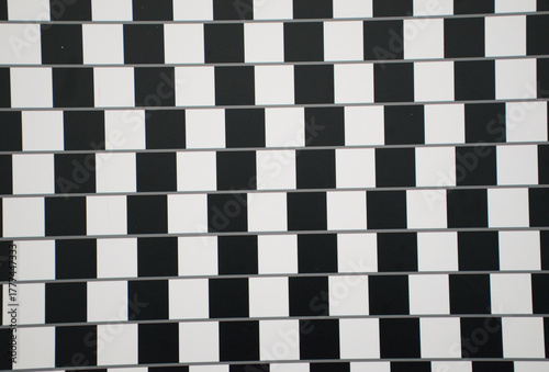 Classic black and white café wall optical illusion featuring a checkerboard pattern that makes parallel lines appear slanted. Striking visual illusion demonstrates how contrasting tones.