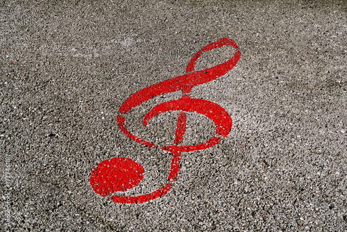 Clef de sol rouge dessinée sur le sol. Symbole musical peint sur le goudron de la rue.
