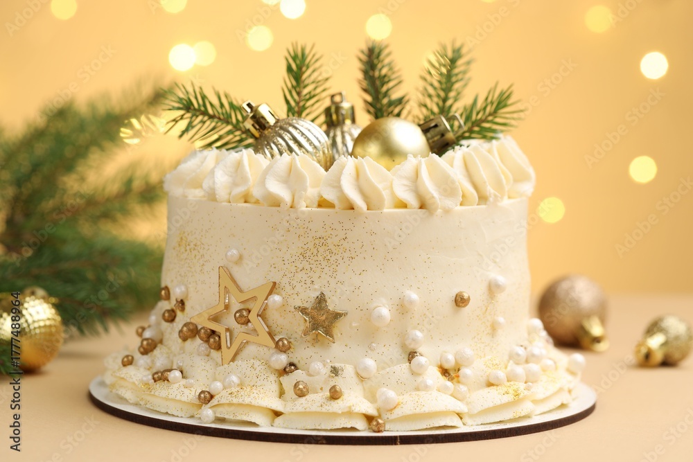 Fototapeta premium Delicious cake with Christmas decor on beige background against blurred lights, closeup. Bokeh effect