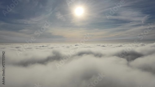 Aerial drone view of industrial chimneys emitting steam above thick fog and clouds on a sunny day, power plant and factory landscape. Panorama above clouds in fog in sunny day. Clouds factory