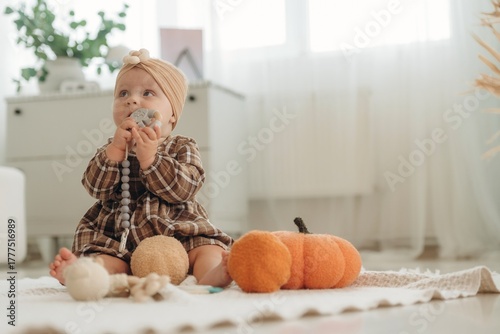 Playing with toy. Cute little baby is sitting on the floor at home with pumpkins toys