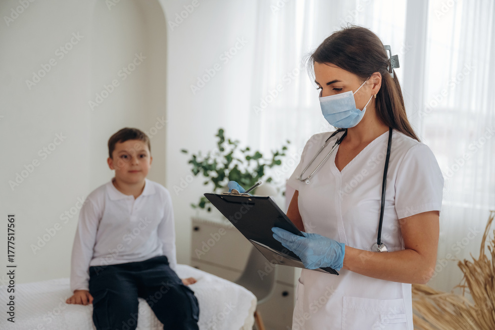 Obraz premium Writing notes into notepad. Boy is in routine appointment in clinic with female doctor