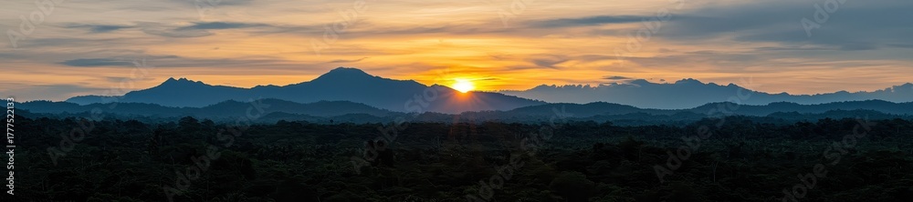 Obraz premium Panoramic view of lush green forest canopy and layered blue mountain ranges at sunrise