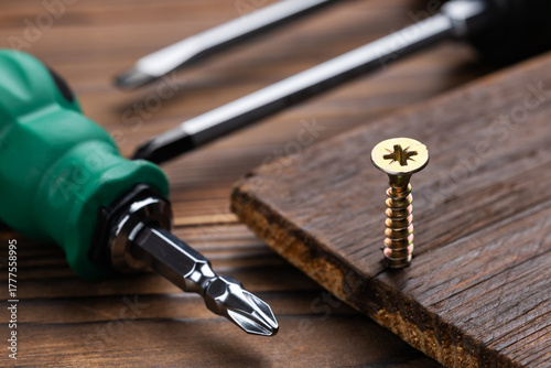 Wallpaper Mural Screwdriver and screws on wooden background. Self-tapping screw. Screws macro photo. Torontodigital.ca