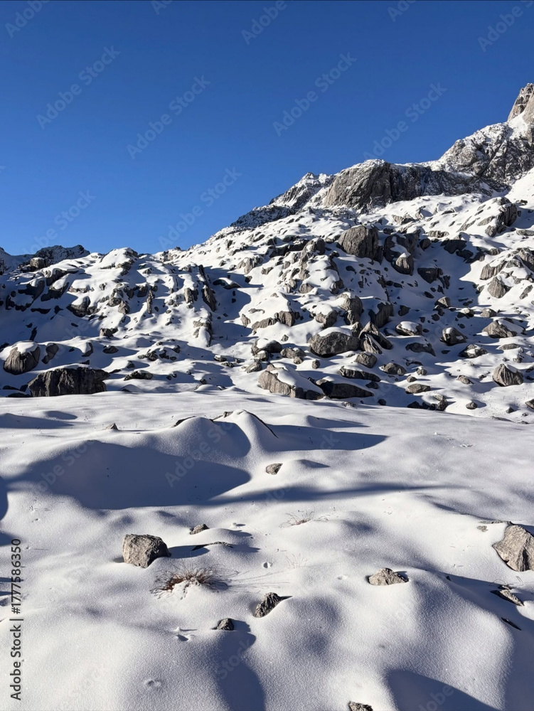 Obraz premium Snow blankets rocky slopes under clear skies.