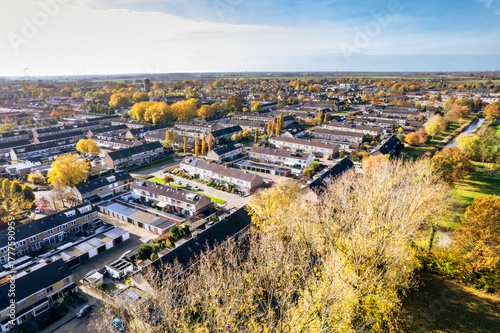 Fototapeta Naklejka Na Ścianę i Meble -  Vibrant autumn landscape shows a small neighborhood surrounded by colorful trees and clear blue skies in a tranquil setting