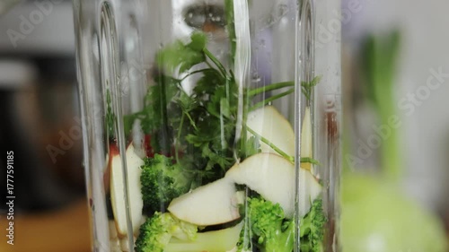 Unknown woman makes healthy detox breakfast smoothie at home. Female hands throws parsley in blender bowl, prepares fresh green vegetarian fruit-greens-vegetables drink to cleanse, provide energy body