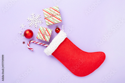 Christmas sock with gifts and decoration on color background, top view