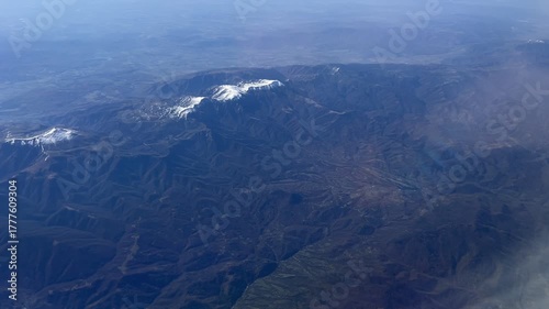 An aerial shot of a hilly green terrain with low clouds lying in the valley