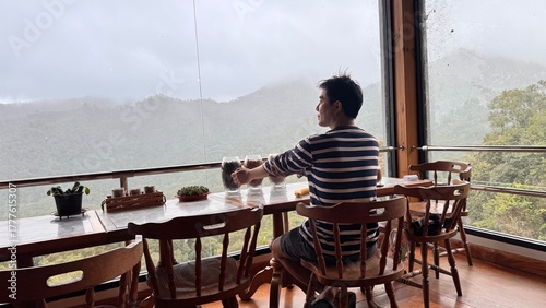 Handsome Man Relaxing in Cafe with Beautiful Morning Misty Valley View