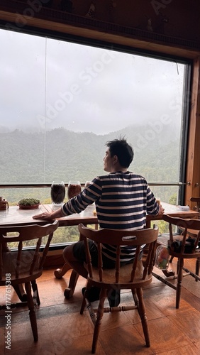 Handsome Man Relaxing in Cafe with Beautiful Morning Misty Valley View