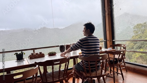 Handsome Man Relaxing in Cafe with Beautiful Morning Misty Valley View