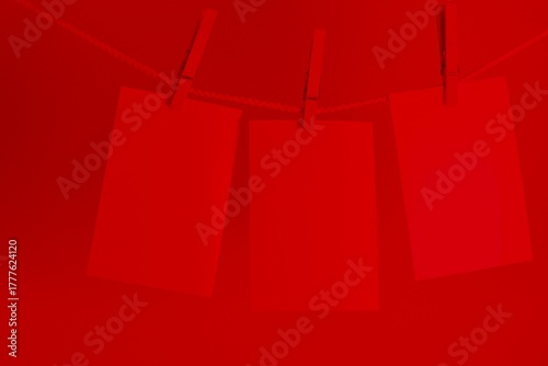 Photography three photos hanging on a rope in the red light of a darkroom