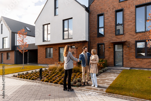 Fotografie Real estate agent shaking hands with happy couple buying house