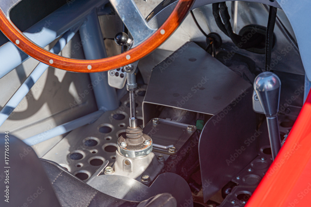 Naklejka premium Close-up of a retro Formula 1 car dashboard, showcasing intricate details and high-performance steering wheel Buttons, dials, and a visible gearbox contrast against the dark interior Soft shadows a