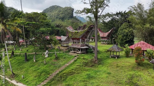 Aerial view of the traditional Tongkonan houses in Ke’te Kesu village, Tana Toraja, Indonesia, surrounded by lush green rice fields.	