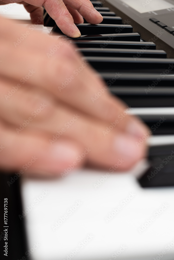 Fototapeta premium Closeup photo of male hands playing on electronic keyboard. Close-up of hand playing piano keys during casual home music practice.