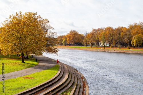 Fototapeta A riverscape view with trees in autumn color over the river Trent in Nottingham, UK