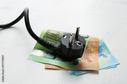 Electrical wire with plug and euro banknotes on white table, closeup