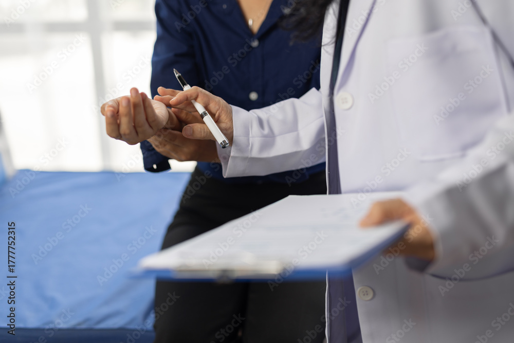 Fototapeta premium Female doctor examining wrist of young female patient sitting on bed in hospital room.