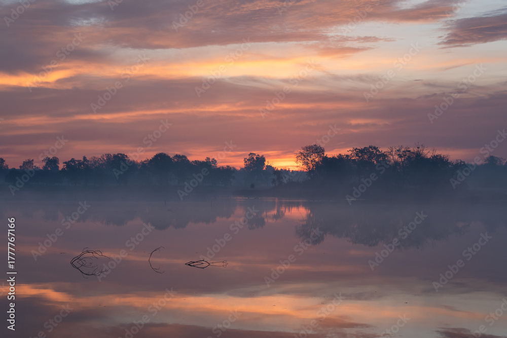Fototapeta premium Jesienny wschó słońca we mgle, nad wodą. 