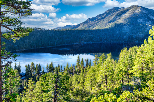 Cascade Lake near Emerald Bay State Park at Lake Tahoe California USA surrounded by lush green pine forest and Sierra Nevada mountains with calm blue water reflecting sky and trees on sunny day