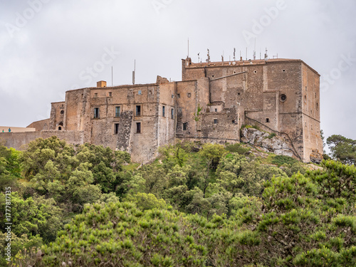 Santuari de Sant Salvador, Mallorca, historic stone castle perched on a hillside, surrounded by lush greenery, stands majestically under an overcast sky, Majorca