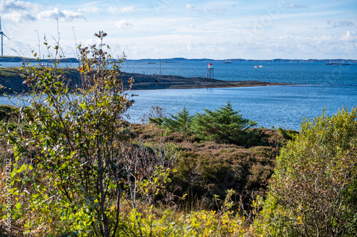 A scenic coastal landscape Kyststien with Kvalen fyr, lighthouse, wind turbines, and a calm sea under a partly cloudy sky, Haugesund, Norway
