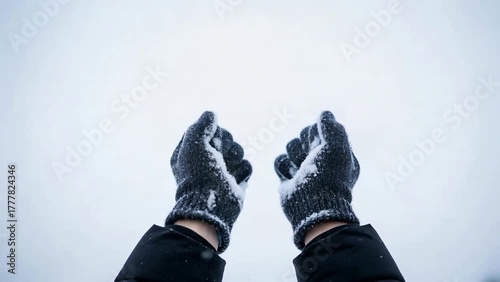 Person Tossing Snow Upward with Gloved Hands in Winter Season