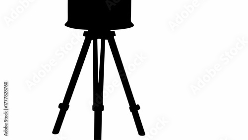 Silhouette of a camera tripod with a circular object mounted on top against a white background