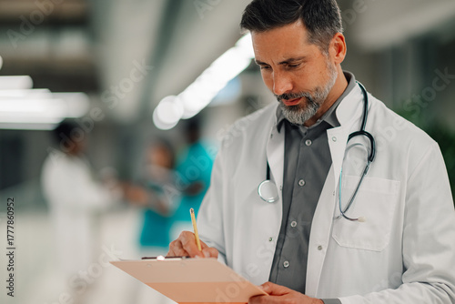 Male doctor writing on clipboard in hospital