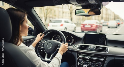 Confident woman driving car with hands on steering wheel in urban city street