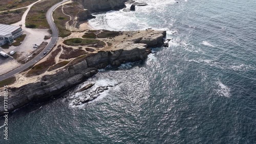 dramatic rocky cliffs meeting the ocean, waves crashing below and scenic coastal landscape.