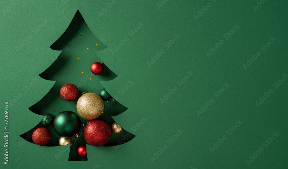 Naklejka premium A green Christmas tree silhouette adorned with red green and gold baubles sits on a matching green background