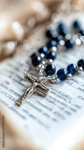 Close-up of rosary beads and crucifix on open bible page, All Saints' Day