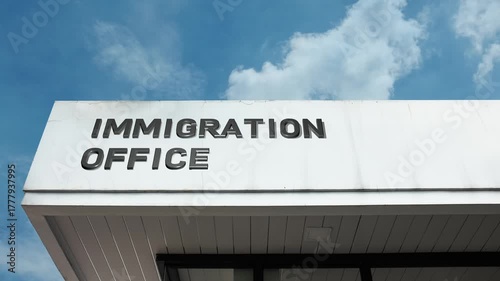 Immigration Office word sign clearly displayed on the official government building facade beneath a clear blue sky, signifying the agency responsible for managing entry, residency, and citizenship