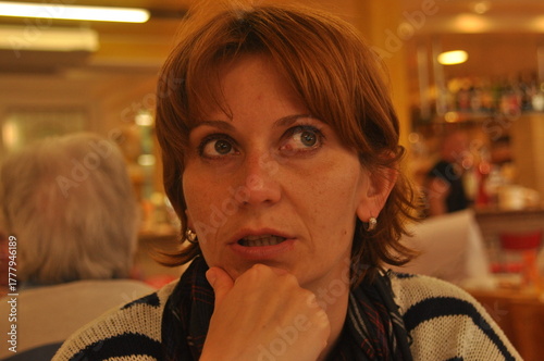 Woman with short hair deep in thought while seated in a cafe, engaged in conversation during the afternoon
