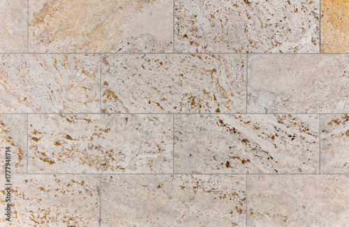 texture of a tiled beige stone wall as background, natural stone wall texture as background. Close-up of a wall clad in limestone