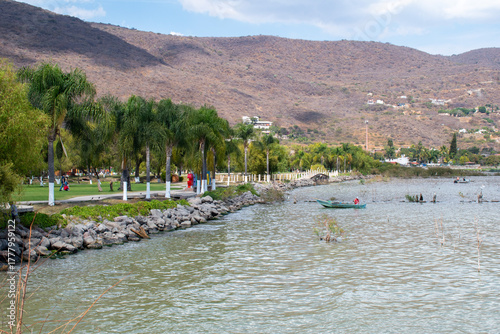 Walking path by Lake Chapala in Jocotepec, Jalisco, with palm trees and rocky shore