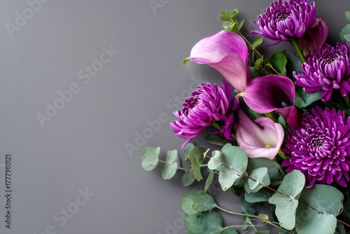 Vibrant Purple Flowers and Green Leaves Arranged on a Gray Surface