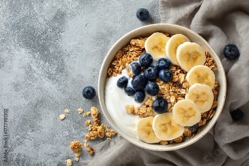Healthy Breakfast Bowl With Yogurt, Bananas, Blueberries, and Granola on a Wo...