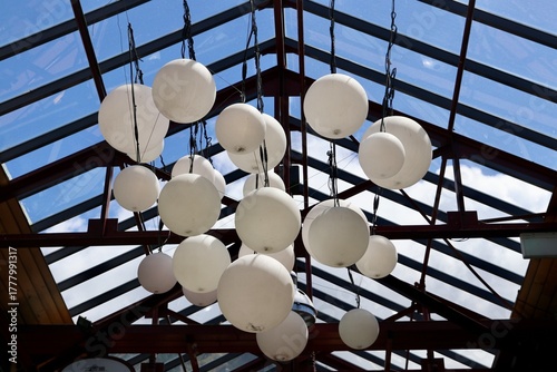 Foto White spherical lights hang beneath a glass ceiling with a blue sky above